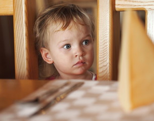 Little girl looking sadly at empty table in the restaurant.