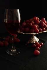 Glass with red wine and grapes on a silver tray