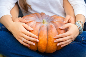 Сouple sitting embracing each other and holding a pumpkin on his lap
