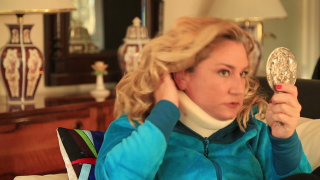 Painful woman with neck brace looking at the mirror