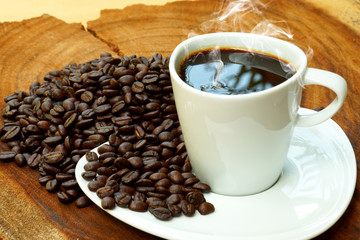 Coffee cup and beans on a wood background.