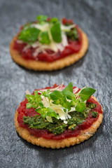 crackers with beetroot pate and pesto on a dark background