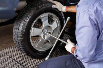 Mechanic Fixing Car Tire With Rim Wrench