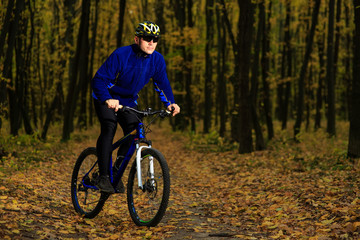 Obraz premium young adult cyclist riding mountain bike in the countryside