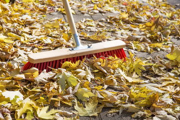 Herbstlaub fegen auf Bürgersteig