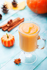 Pumpkin smoothie with pie spices on a turquoise wooden background 