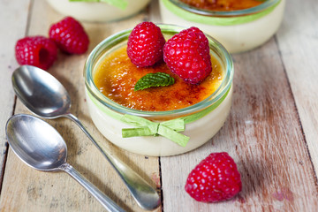 The creme brulee in glass dish with mint and raspberries