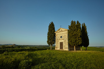 Fototapeta na wymiar Little chapel surrounded by cypress trees. Tuscany, Italy