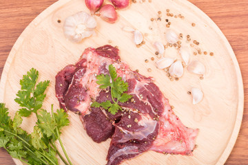 fresh raw beef meat slices and garlic, pepper on wooden