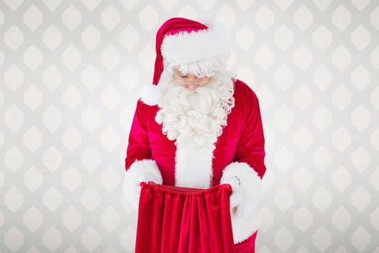 Composite image of santa claus looking in sack
