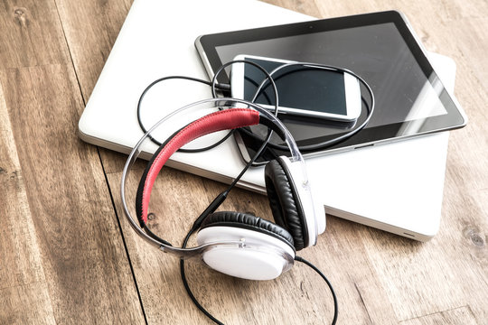 Digital devices and Headphones on a wooden Desktop.