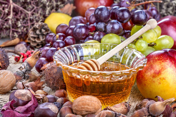 Autumn fruits, nuts and vegetables with honey on the table