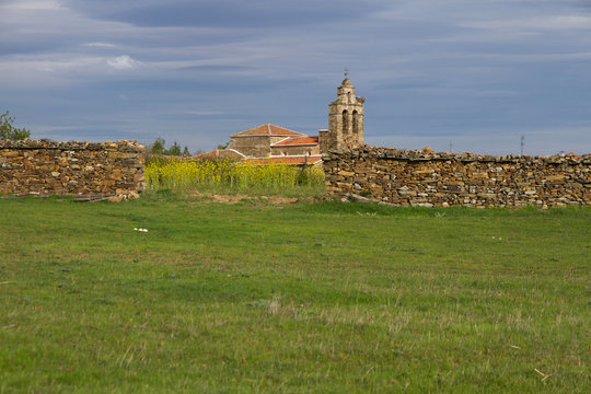 Pradera y campos con cercado de piedras e iglesia en Luyego, Leon, Espa&ntilde;a 