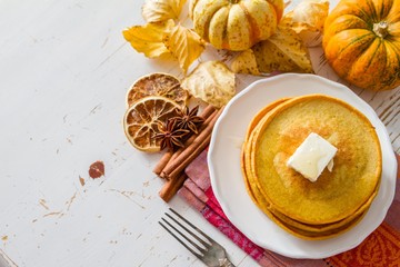 Pumpkin pancakes on white plate with butter and honey