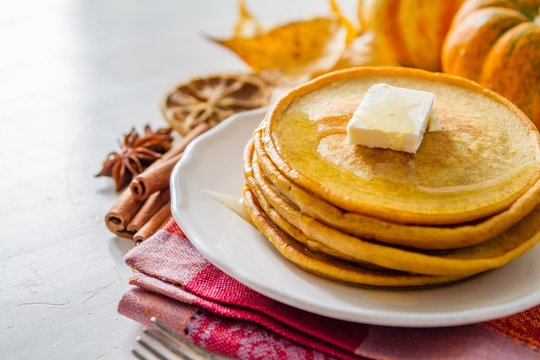 Pumpkin pancakes on white plate with butter and honey