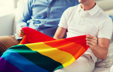 close up of male gay couple holding rainbow flag