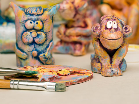 Paintbrush, clay panel and clay figurines of cat and monkey.small DoF focus put only to brush