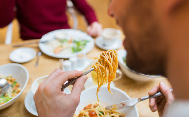 close up man eating pasta for dinner at restaurant