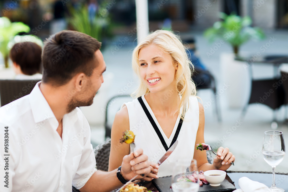 Poster happy couple eating dinner at restaurant terrace