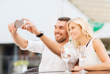 happy couple taking selfie with smartphone at cafe