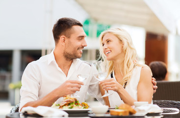 Obraz na płótnie Canvas happy couple clinking glasses at restaurant lounge