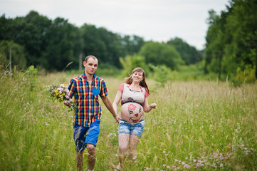 Happy young couple expecting baby, pregnant woman with painted b