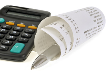 Ticket de caisse enroulé autour d'un stylo et calculatrice 