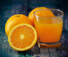 Orange juice glass and fresh oranges on wood