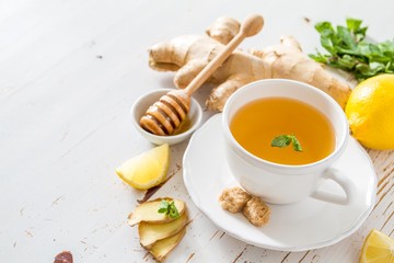 Ginger tea and ingredients on white wood background