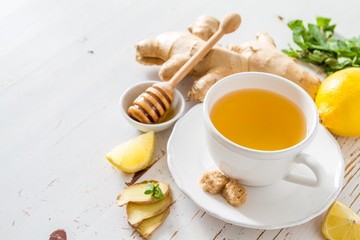 Ginger tea and ingredients on white wood background
