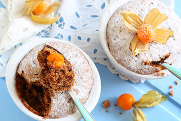 two chocolate muffins in ceramic forms sprinkled with powdered s
