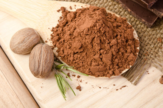 nutmeg with a sprig of rosemary and cacao powder in the wooden s