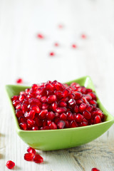 pomegranate seeds in a bowl on wooden surface