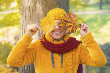 woman in park holding leaves in front of her face