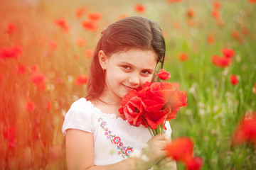 Obraz na płótnie Canvas Closeup of cute girl in poppy field holding flowers bouquet outdoors. Girl in poppies. Happy kid with poppies.