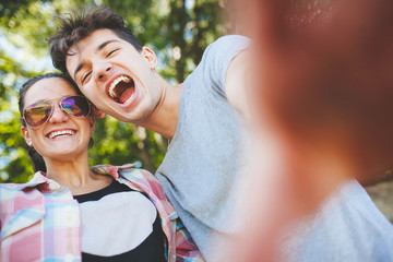 Obraz premium Happy teenagers couple laughing outdoors. summer holidays and teenage concept - young people having fun outside