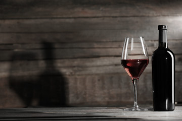 Wine bottle with glass on wooden background,  black and white retro stylization