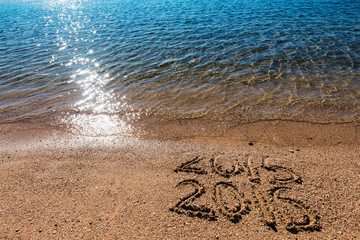  New Year 2016 is coming concept - inscription 2015 and 2016 on a sea sand with sunlight