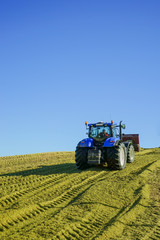 Blauer Traktor mit Planierschild beim verdichten der Maissilage