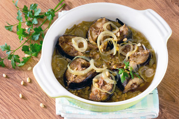 Baked fish (mackerel) on a bed of onion with pine nuts