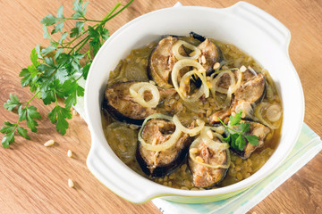 Baked fish (mackerel) on a bed of onion with pine nuts