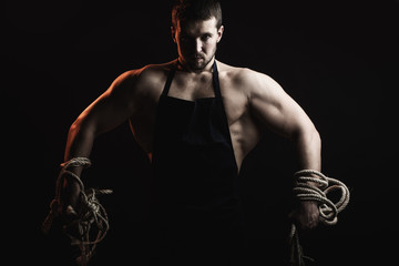 Fototapeta na wymiar Muscular man in apron with rope