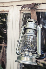 Shining metal kerosene lamp hangs on white frame