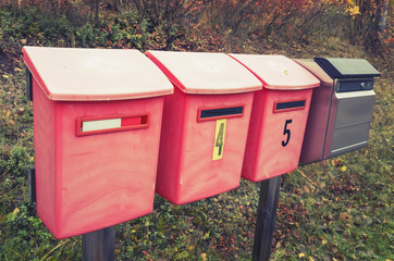 Old red post boxes on a roadside in a row