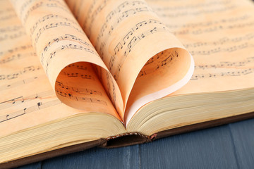 Book pages curved into heart shape on table close up