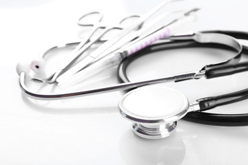 Stethoscope and medical instruments on white background, close up