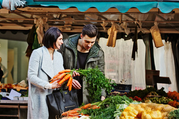 Couple looking at carrots on a market stand