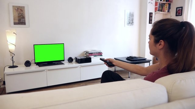 Watching Television Green Screen Changing Channels - 1080p. Girl watches television with green screen / shot behind model's shoulders

