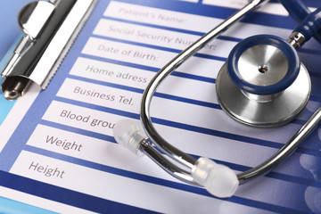 Medical stethoscope and clipboard on blue background