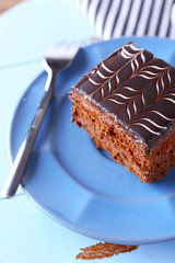 Sweet chocolate cake on blue plate on wooden table, close up